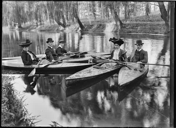 Three men and two women in tethered canoes, 1900