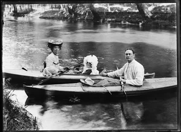 Man, woman and child in canoes, 1900