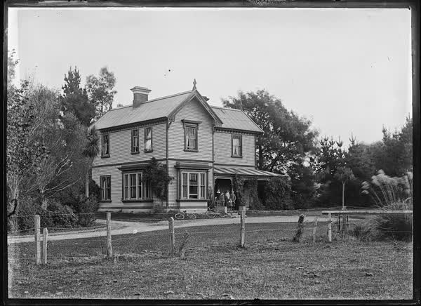 Man and six children standing on front steps of a house, 1900