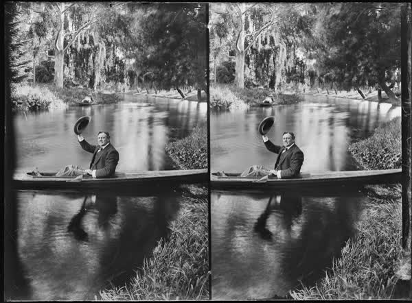 Man waving a hat in a canoe on the Avon River, 1900