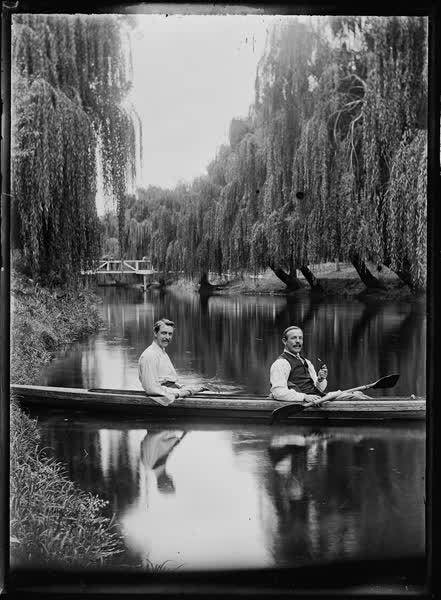 Two men, one with a tobacco pipe, in a double canoe on the Avon River, 1900
