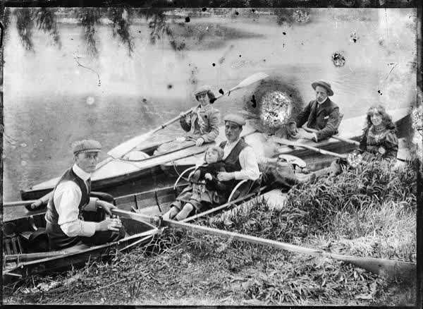 Four men, one woman, one girl and a younger child in a rowboat, 1900