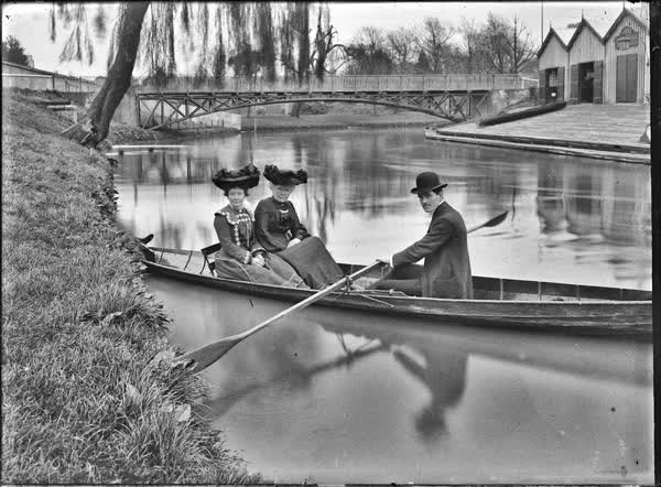 Two women and a man in a rowboat by the Antigua Boat Sheds, 1900