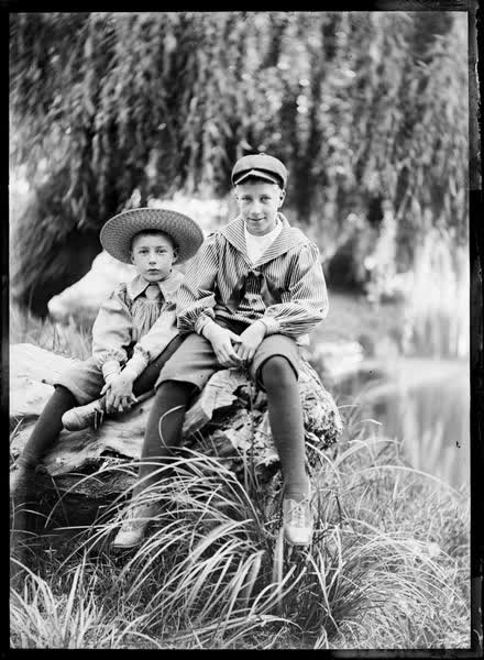 Two boys seated on a log by the Avon River, 1900