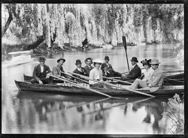 Eight men and two women in canoes and rowboats, 1900