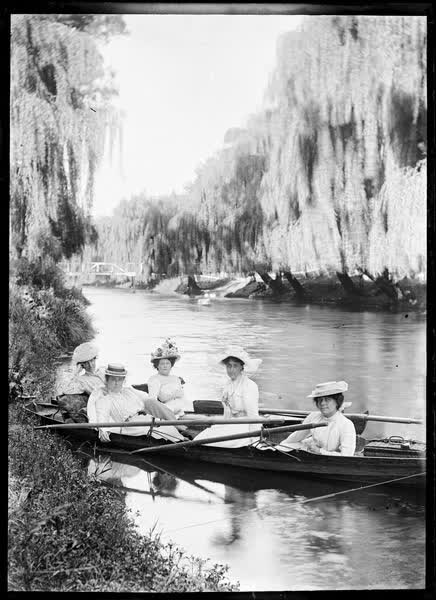 Five women with a picnic basket in two rowboats, 1900