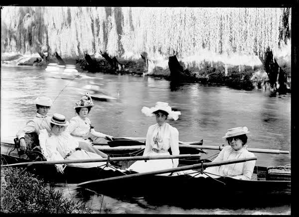 Five women with a picnic basket in two rowboats, 1900