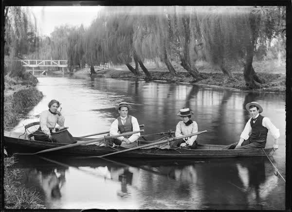 Two women and two men in a tethered double rowboat, 1900
