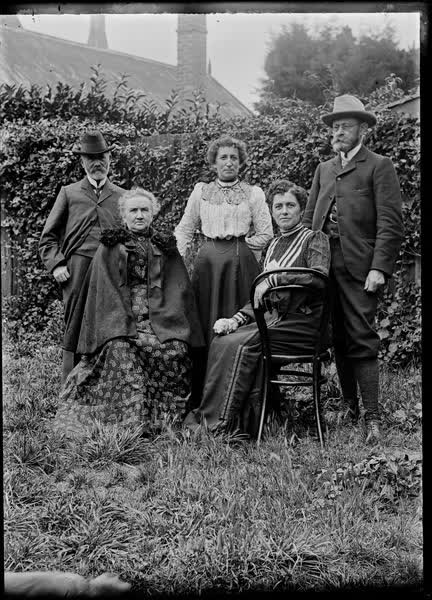Three women and two men in a garden, 1900