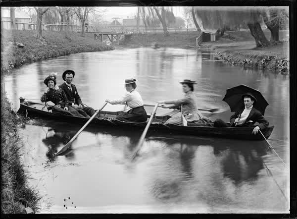 Three women and two men in a double rowboat, 1900