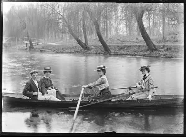 Three women and a man in a double rowboat, 1900