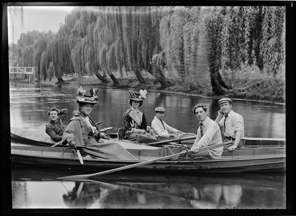 Four men and two women in rowboats and a canoe, 1900