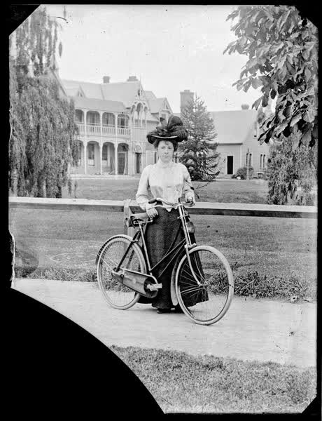Woman standing with a bicycle, 1900