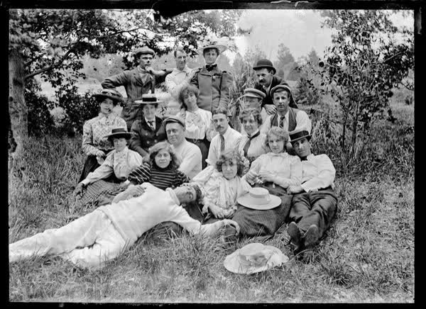 Group of eighteen men and women outdoors, 1900