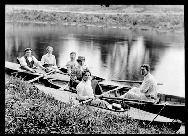 Two men and four women in canoes and rowboats, 1900
