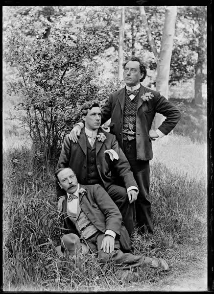 Three men in Hagley Park, dressed in suits with floral buttonholes, 1900