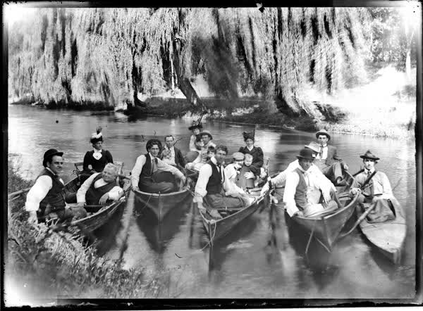 Sixteen men, women and children in rowboats and canoes, 1900