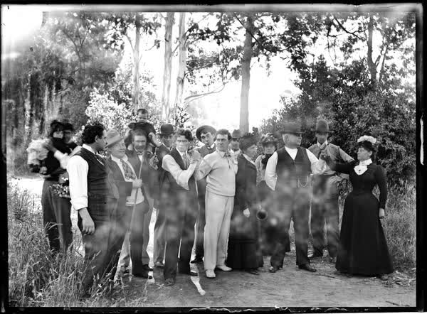Sixteen men, women and children on a path, 1900