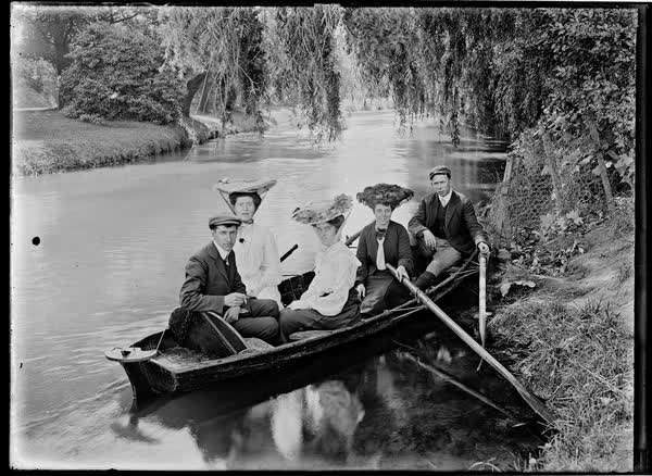 Three women and two men in a double rowboat, 1900