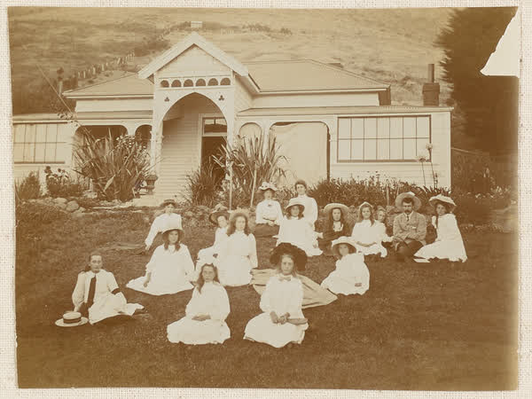 Miss Mouldey and group of  girls sitting on lawn, 1910