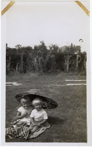 Connie and Ray Macefield sitting on grass with an umbrella, 1933