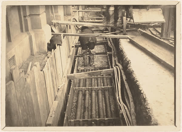 Worker covering ducts in trench, 1920