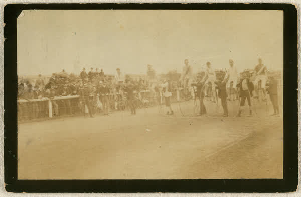 Six unidentified men on penny-farthings at start line of race, 1887