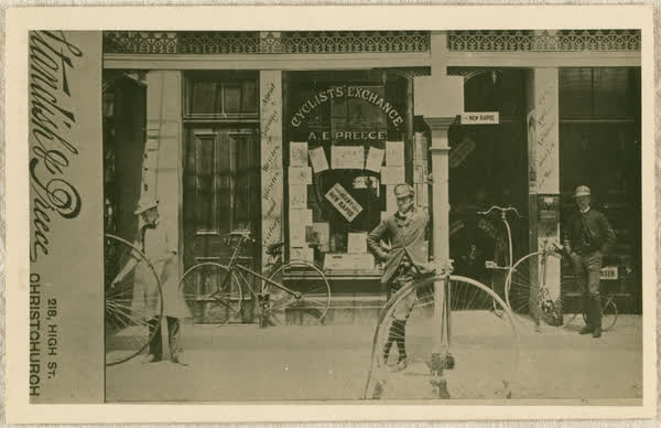 Three men with penny-farthings outside Cyclists Exchange, 1885