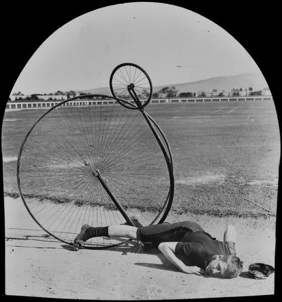 Fred Wood lying on the ground with a penny-farthing, 1880