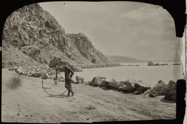 Unidentified man with a penny-farthing at Shag Rock, 1890