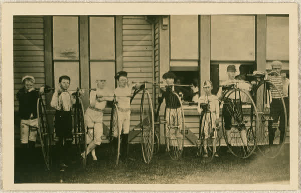 Eight boys holding penny-farthing bicycles, 1890