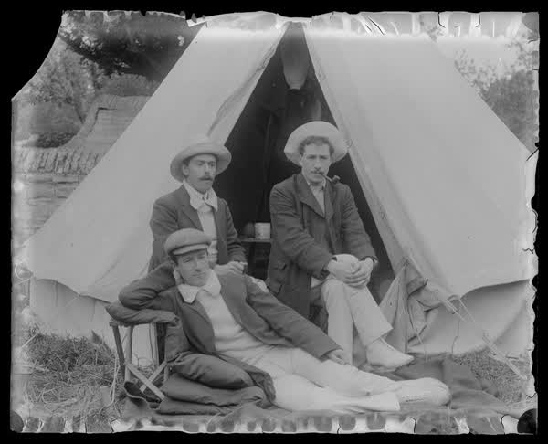People relaxing outside a tent, 1900