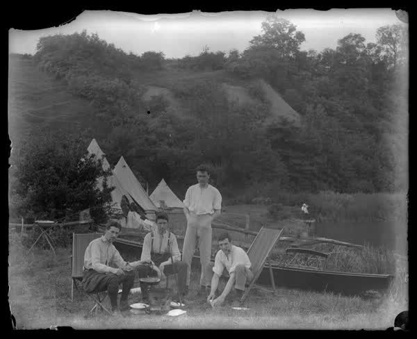 Cooking food next to river, 1900