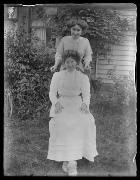 Portrait of two women outside a weatherboard house, 1900