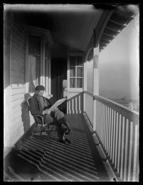 Man sitting on the verandah reading, 1900