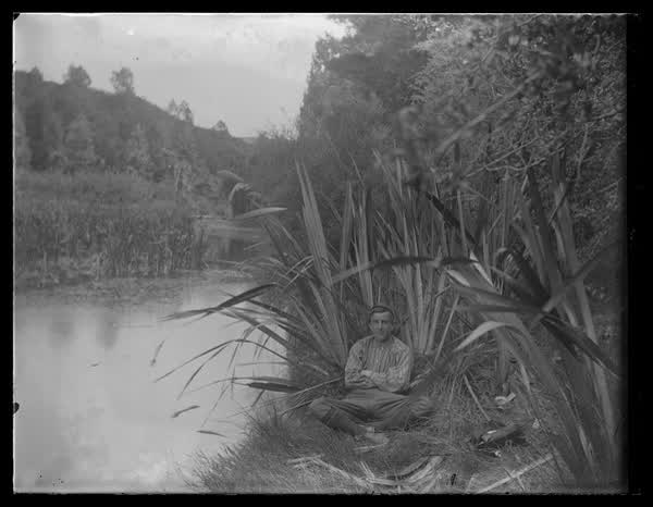 A young man sitting on the riverbank, 1900