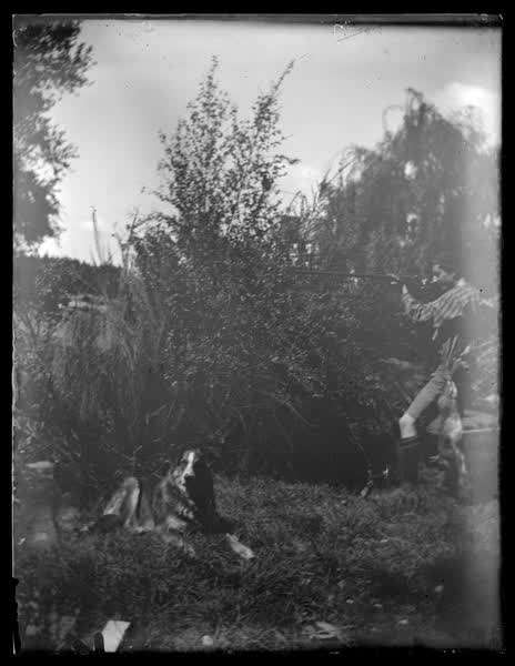 A boy with a shotgun next to a dog, 1900