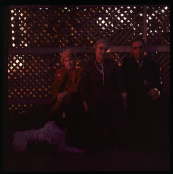 Three people sitting on a bench, 1950