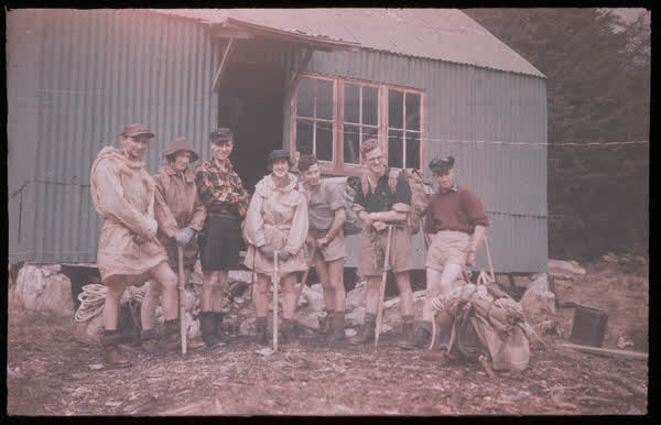 Seven people standing near the old Anti Crow Hut, 1950