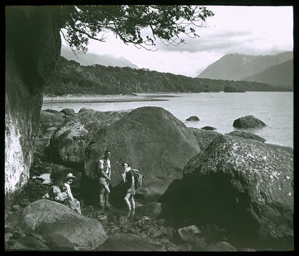 Three people near a large boulder, 1950