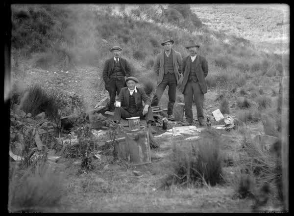 Four men beside a campfire, 1900