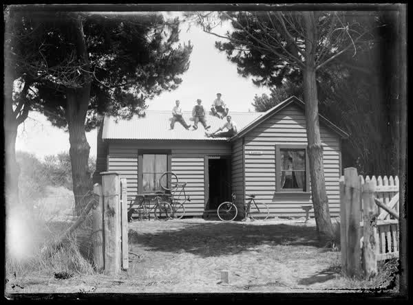 Men sitting on a house roof, 1900