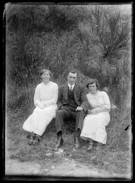 Man and two women in grass, 1900