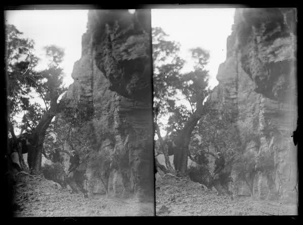 Three men at the bottom of a cliff, 1900