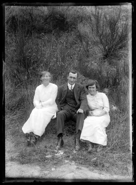 Man and two women in grass, 1900