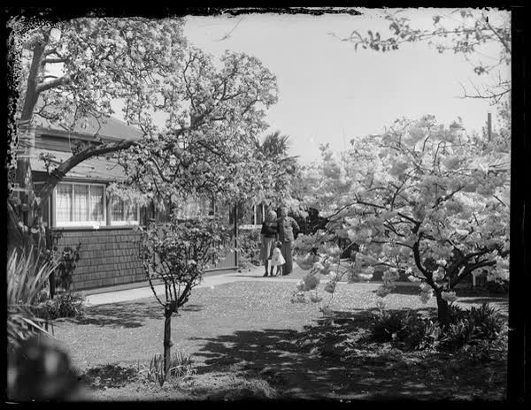 Ruth and John Sutton with a child in a garden, 1950