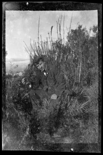 Man sitting in bushes, 1900