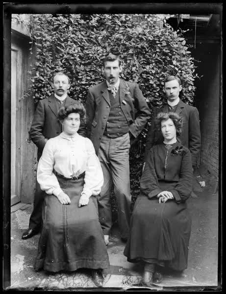 Group portrait in front of a bush, 1910