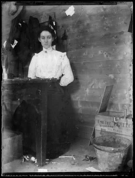 Woman standing by a table, 1900