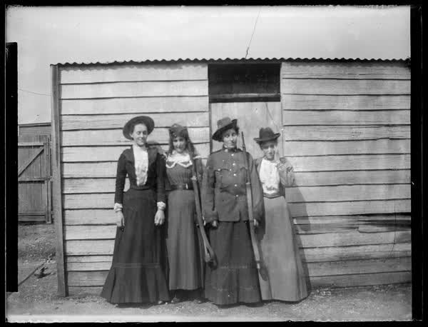 Four women standing in front of a shed, 1900